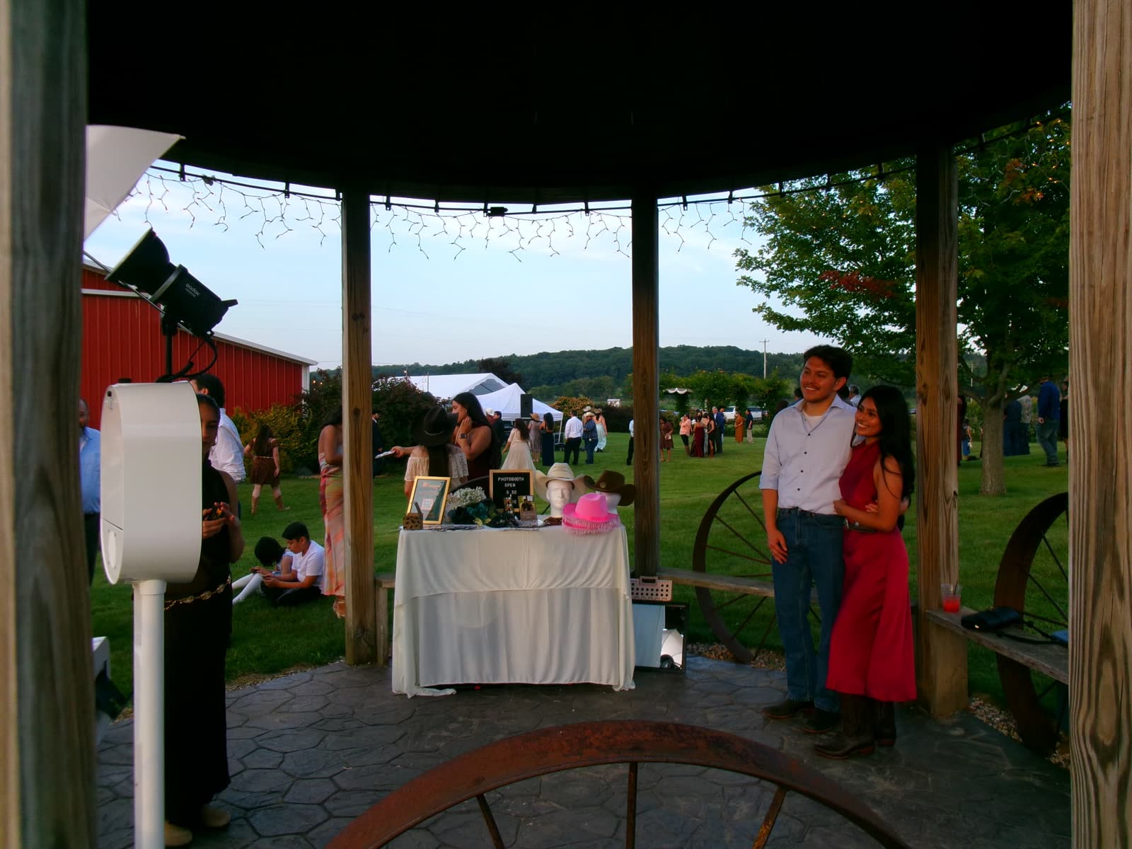 Memento photo booth and prop table set up in a gazebo at a countryside barn wedding