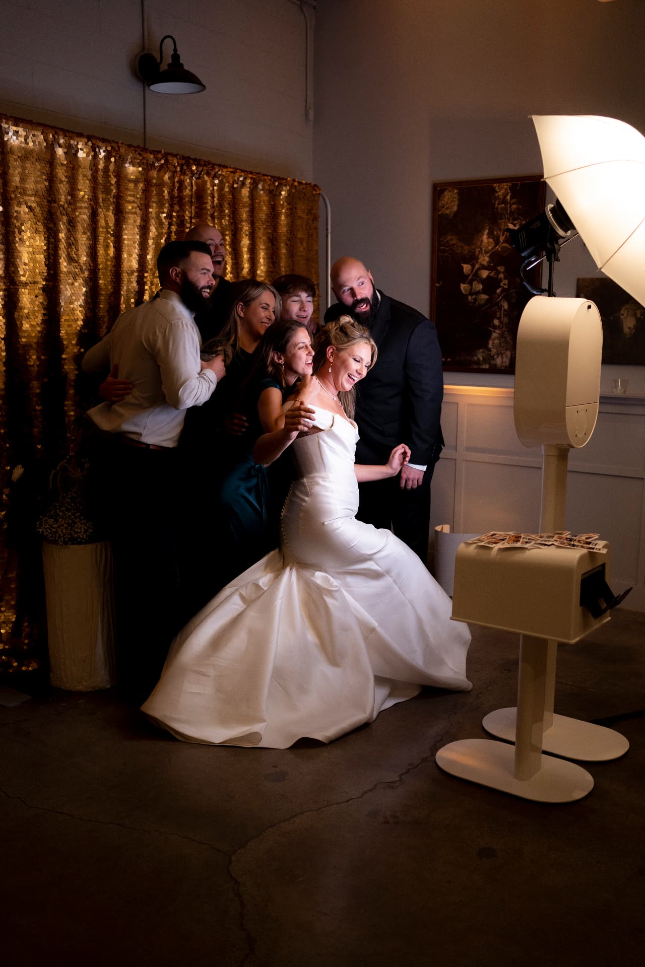 A wedding party laughing in front of a gold sequin backdrop