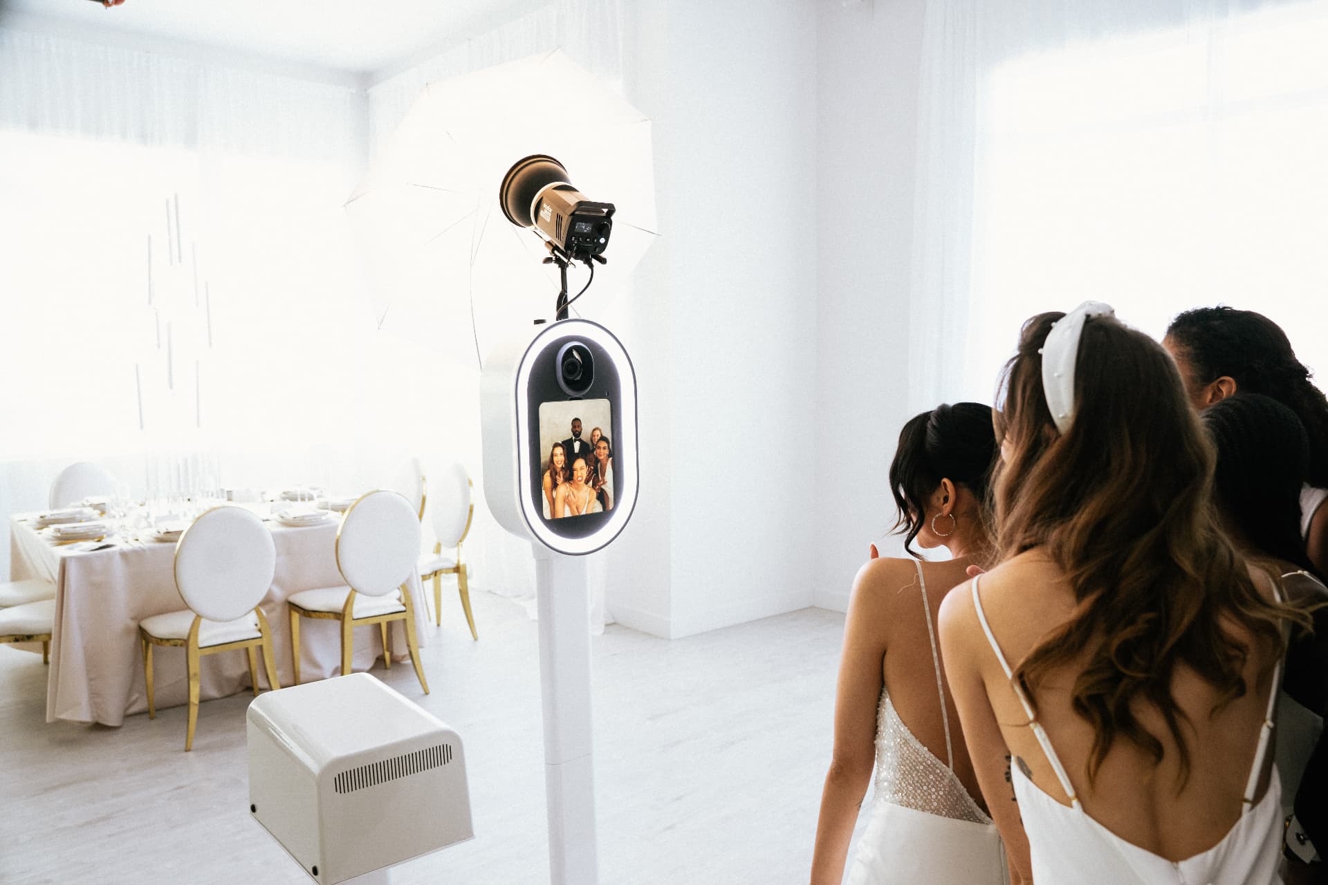Bridesmaids gathered around the Memento photo booth at a wedding reception