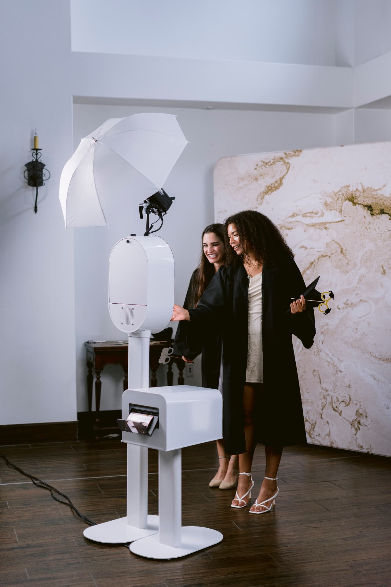 Two graduates using the Memento photo booth and printer station