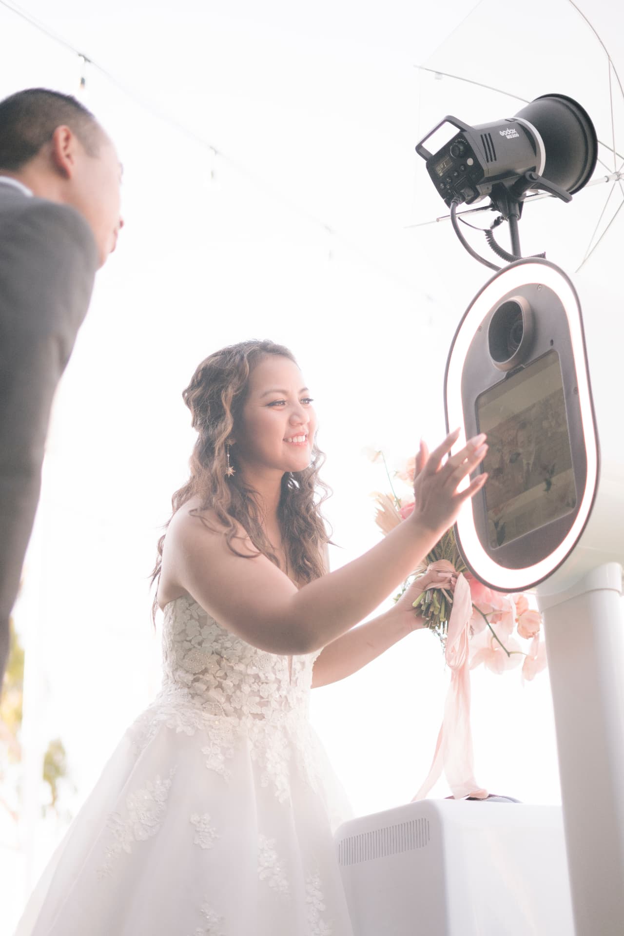 A bride touching the Memento photo booth screen in bright daylight
